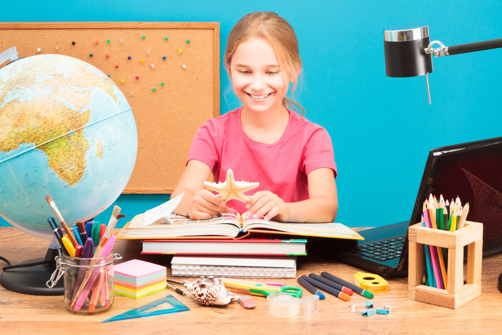 Молодая улыбающаяся девушка делает домашнее задание
 - Фото, изображение