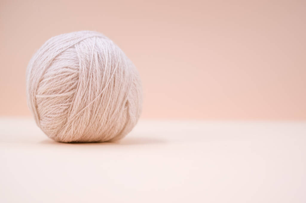 A vertical shot of isolated grey yarn on a beige background with text space - Photo, Image
