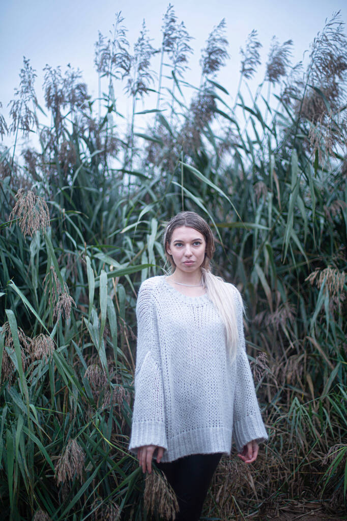 Młoda Europejka w białym swetrze w wysokiej trawie - Zdjęcie, obraz