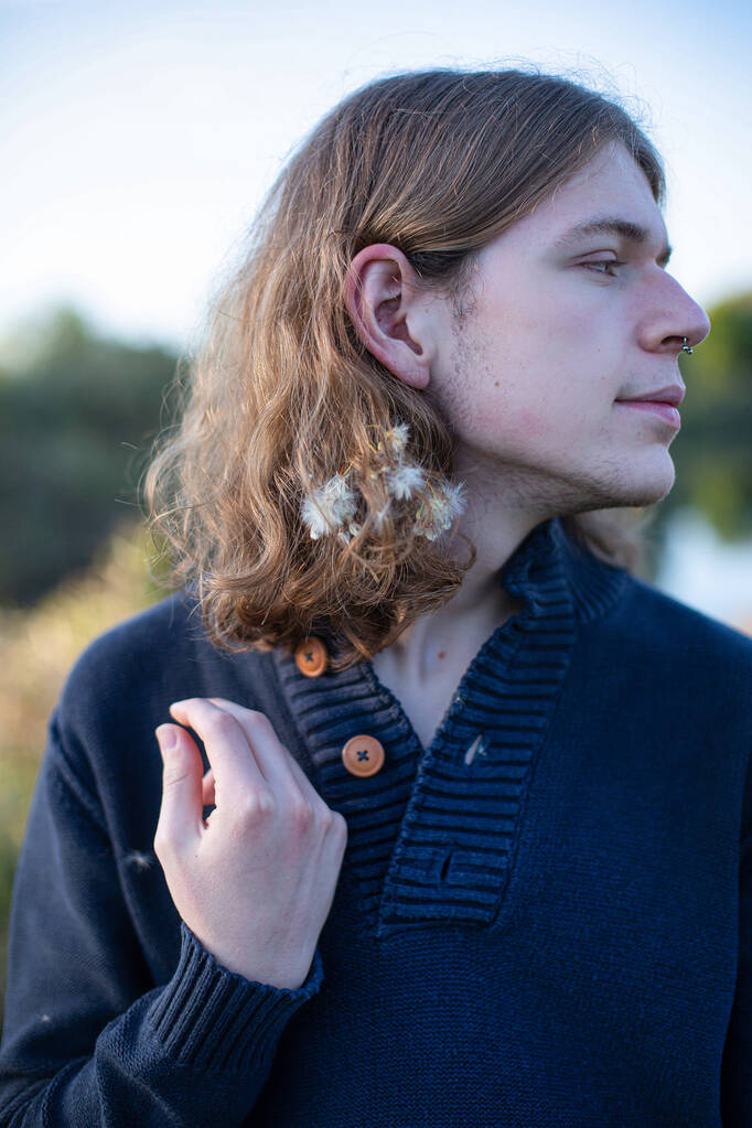 Fehér európai fiatalember hosszú szőke hajjal, erdő mögötte - Fotó, kép