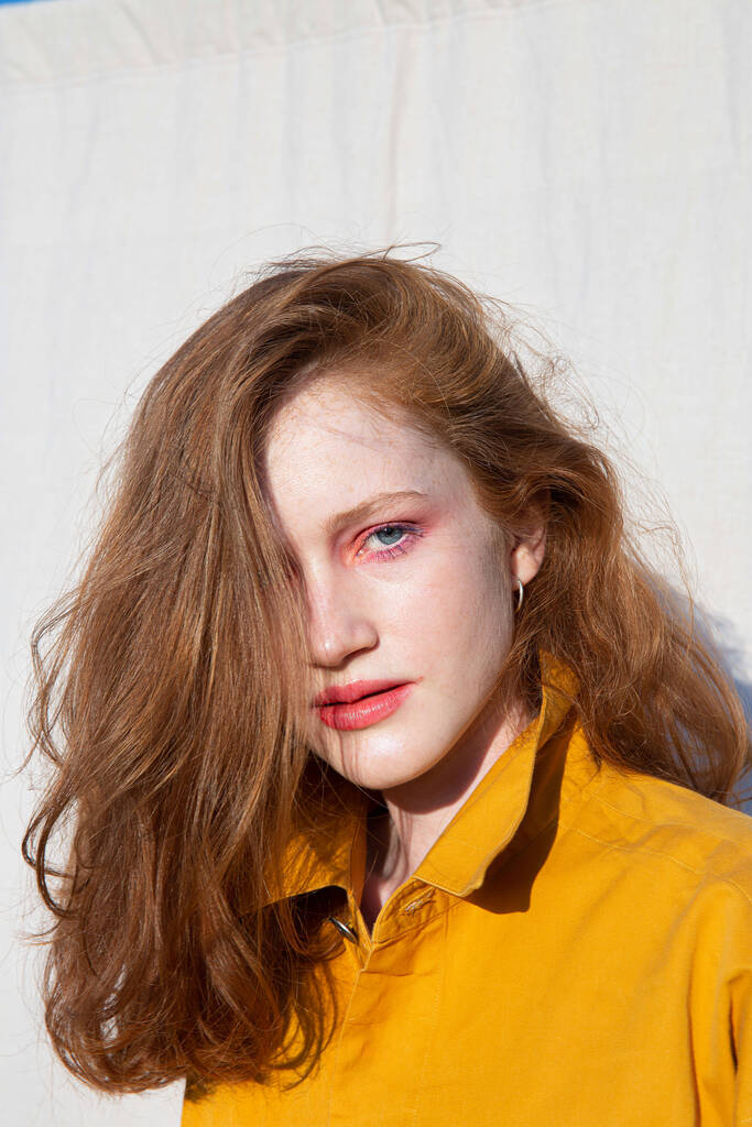 Europäisches weißes Mädchen mit hellem Make-up in der Nähe der Mauer - Foto, Bild