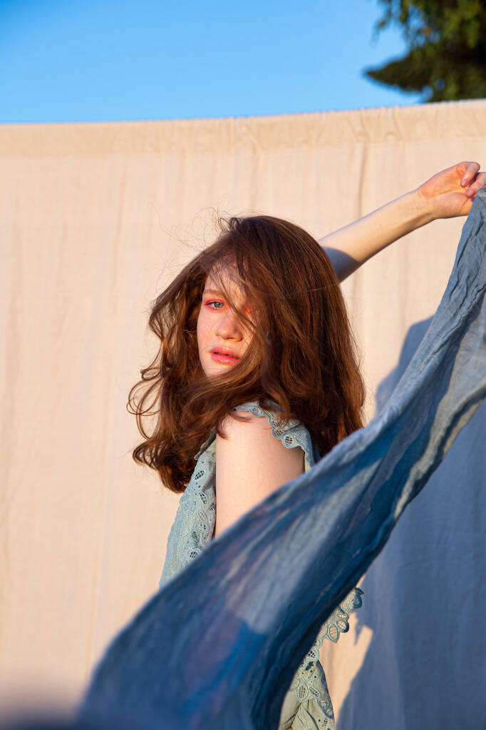 Przeprowadzka młoda Europejka dziewczyna z jasnym makijażu z kawałkami niebieskiej tkaniny - Zdjęcie, obraz