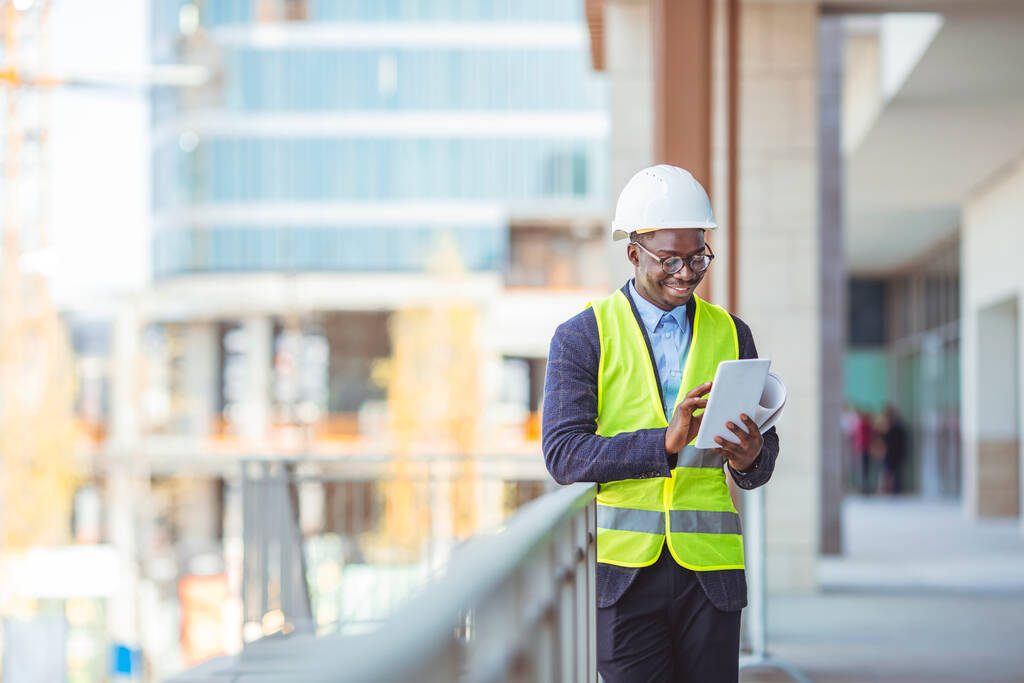 Portrait of smiling Engineer / Architect looking at camera. Working on a new office building. Happy mid adult engineer. Man engineer walking on construction site, holding tablet. - Photo, Image