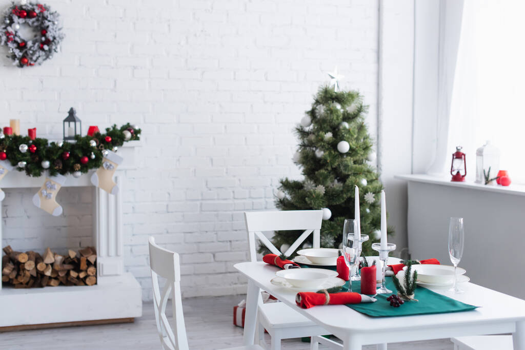 Modern oturma odası, dekore edilmiş şöminesi, Noel ağacı ve şenlikli akşam yemeği için servis edilen masa. - Fotoğraf, Görsel