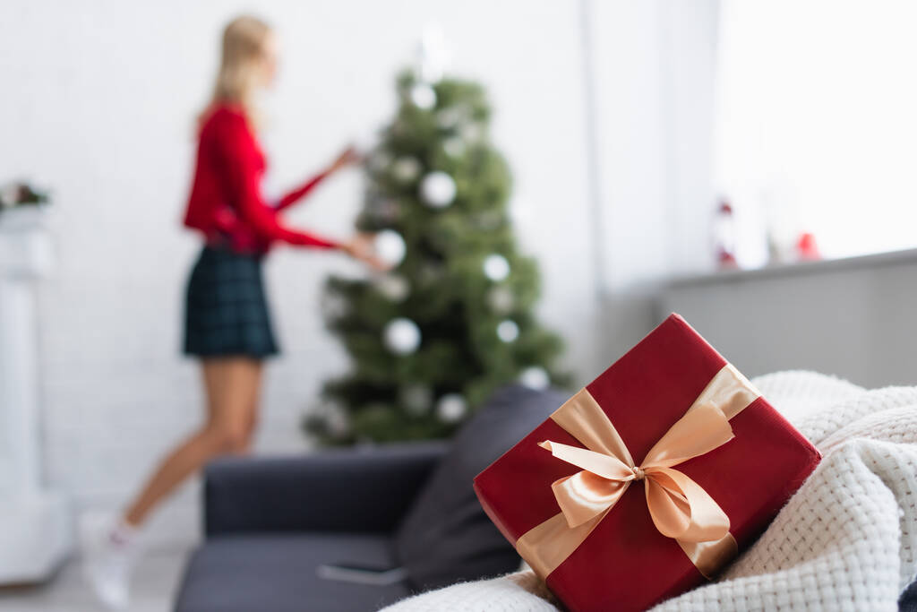 szelektív fókusz ajándék doboz dekoratív szalag közelében nő és karácsonyfa elmosódott háttér - Fotó, kép