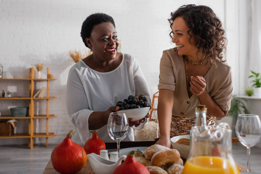 Mère afro-américaine et fille adulte servant le dîner de Thanksgiving ensemble  - Photo, image