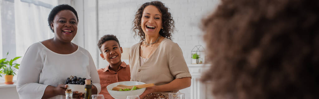 Alegre familia afroamericana con comida mirando a chica borrosa durante la celebración de Acción de Gracias, pancarta  - Foto, Imagen