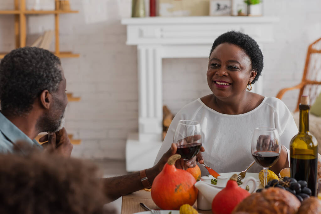 Starší africká americká žena při pohledu na manžela s vínem během večeře na Díkůvzdání  - Fotografie, Obrázek