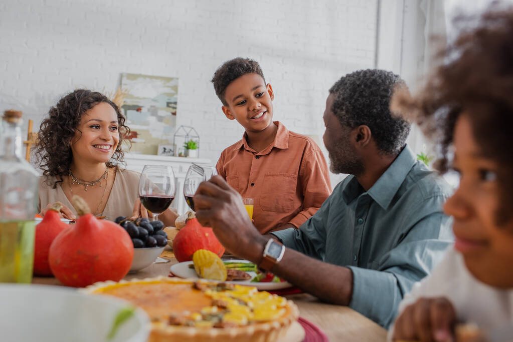 smiling african american boy talking to grandfather during thanksgiving dinner with family - Photo, Image