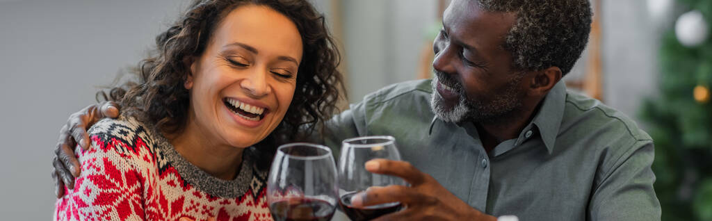 alegre afro-americano pai e filha clinking copos de vinho tinto durante a celebração do Natal, banner - Foto, Imagem