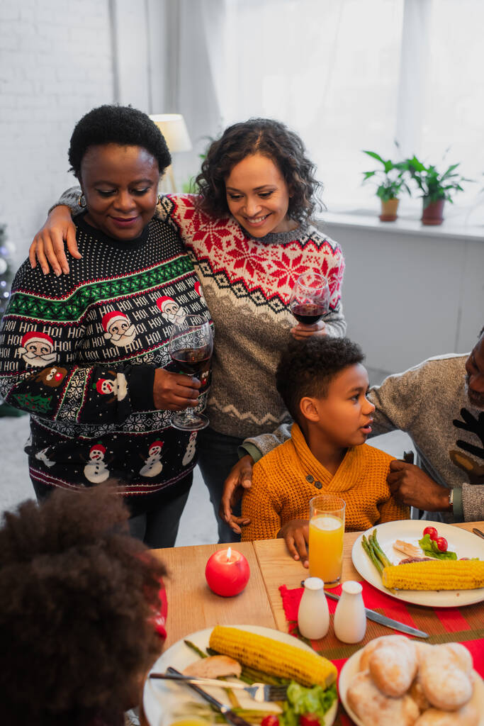 幸せなアフリカ系アメリカ人女性家族とクリスマスディナーの間に母親を受け入れる - 写真・画像