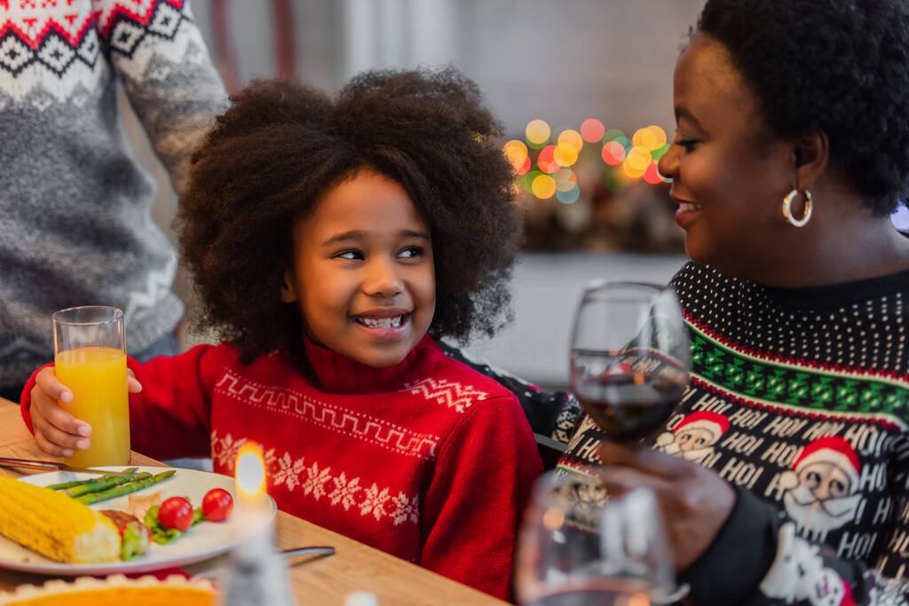 クリスマスディナーの時アフリカ系アメリカ人の女の子が幸せなおばあちゃんの近くで - 写真・画像