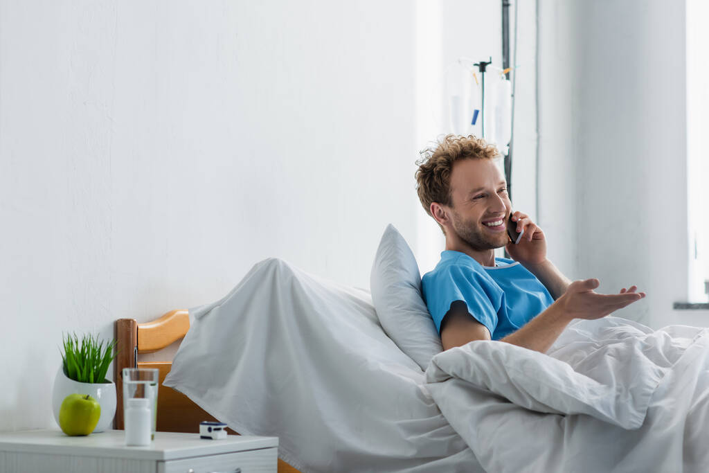 homem alegre falando no smartphone enquanto gesticulando no hospital - Foto, Imagem
