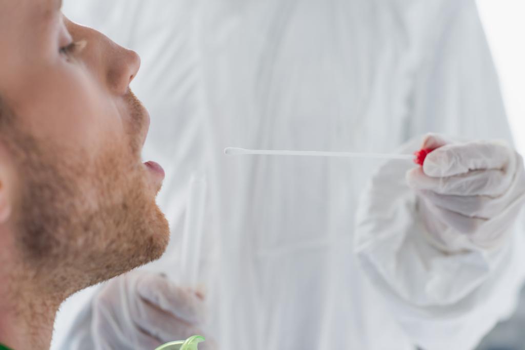 orvos vegyvédelmi ruha gazdaság tampon közelében beteg nyitott szájjal  - Fotó, kép