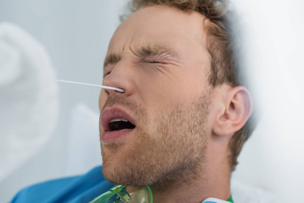 arts met wattenstaafje in de buurt van de neus van de patiënt tijdens de pcr-test - Foto, afbeelding