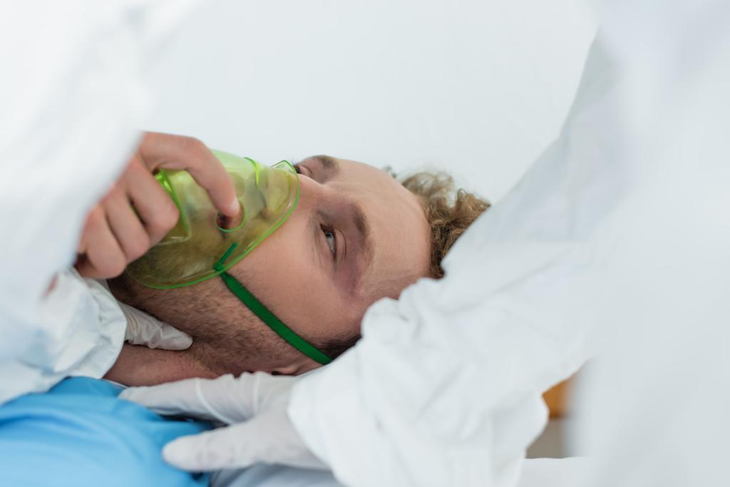 лікар у костюмі з туманом і латексні рукавички, що вивчають пацієнта в кисневій масці в лікарні
  - Фото, зображення