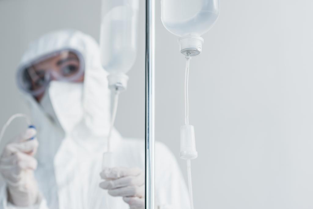arts in persoonlijke beschermingsmiddelen en brillen met katheter op druppelteller - Foto, afbeelding