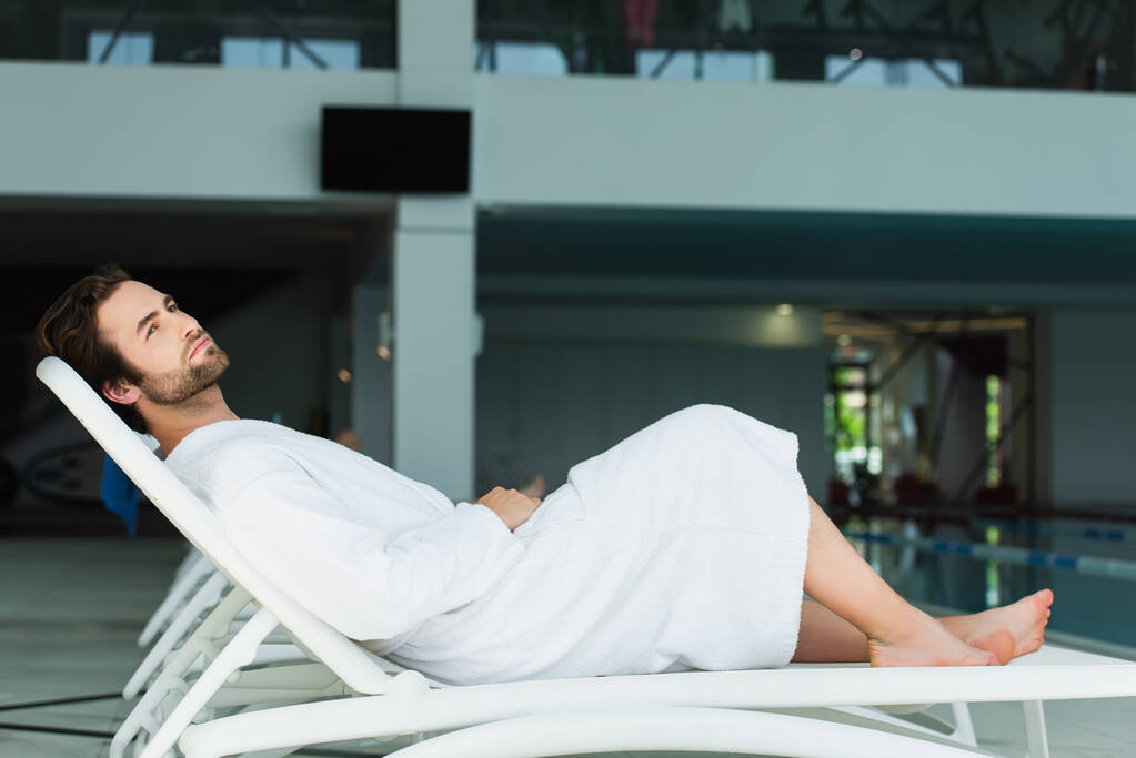 Молодой человек отдыхает на шезлонге в спа-центре  - Фото, изображение
