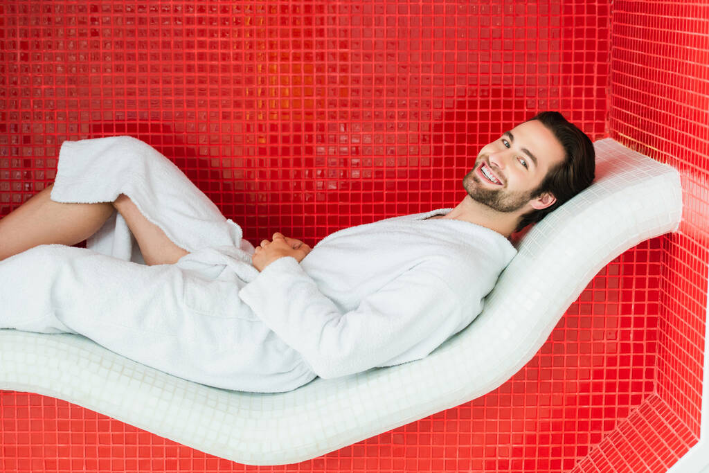 Hombre positivo relajante en silla de salón en el centro de spa  - Foto, Imagen
