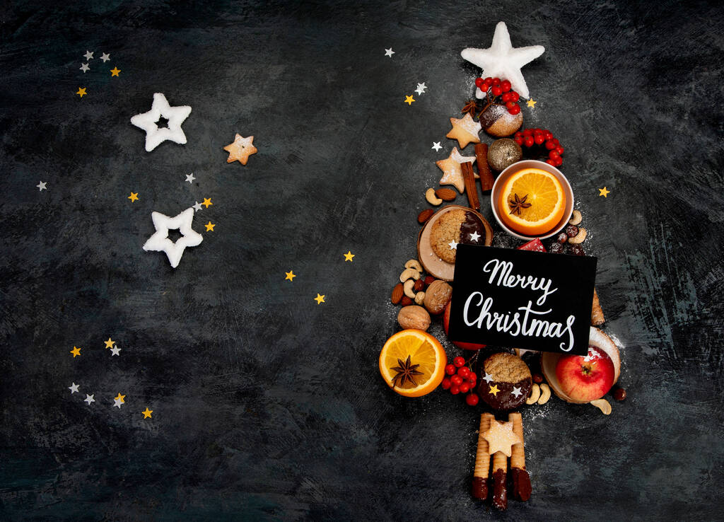 Χριστουγεννιάτικο δέντρο φτιαγμένο από φαγητό σε σκούρο φόντο. Εορταστική σύνθεση. Πάνω όψη, αντιγραφή χώρου - Φωτογραφία, εικόνα