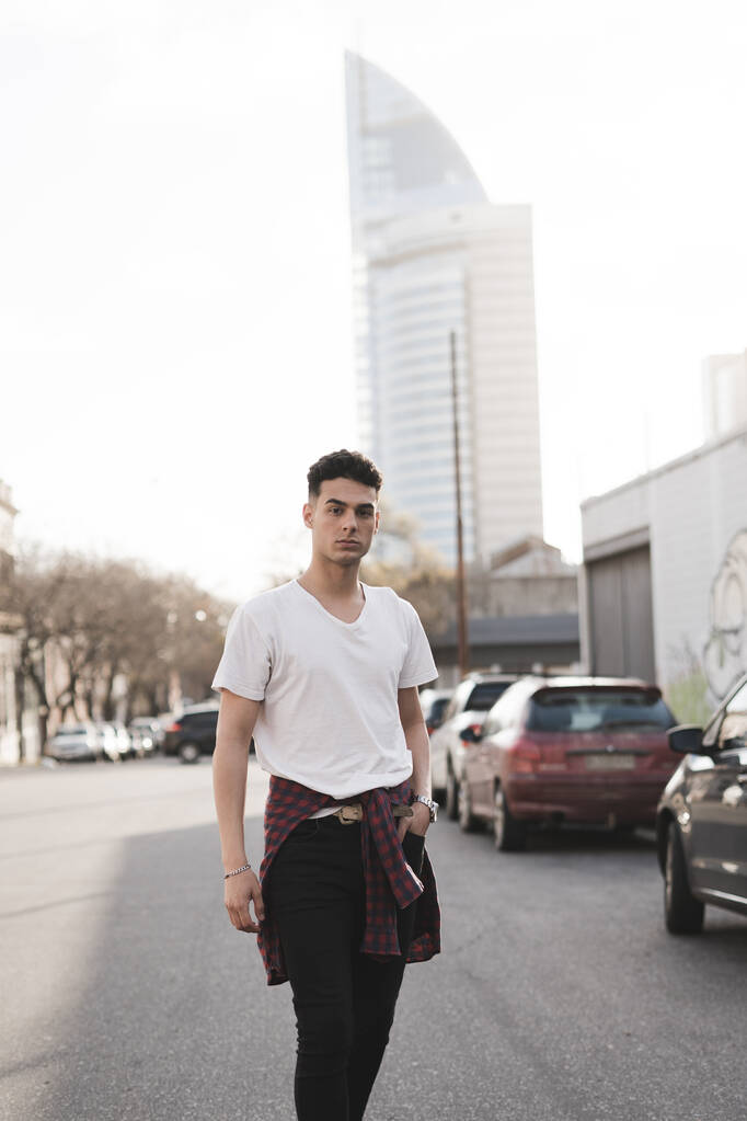 Een verticaal schot van een jonge stijlvolle blanke man poseren op de straat - Foto, afbeelding