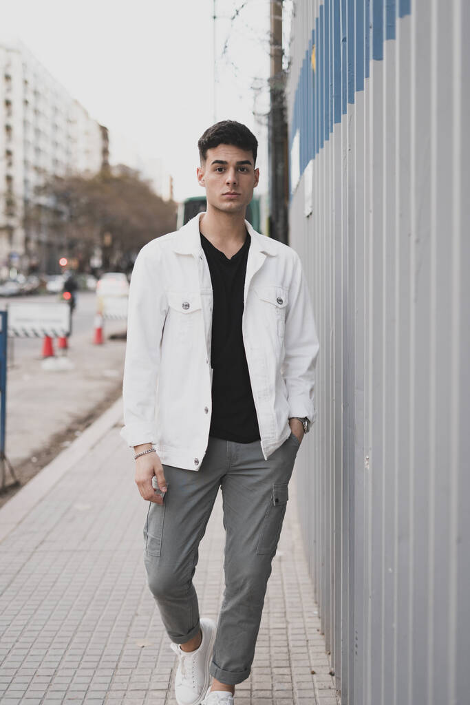 A vertical shot of a young stylish caucasian man in a white jacket outdoors - Photo, Image