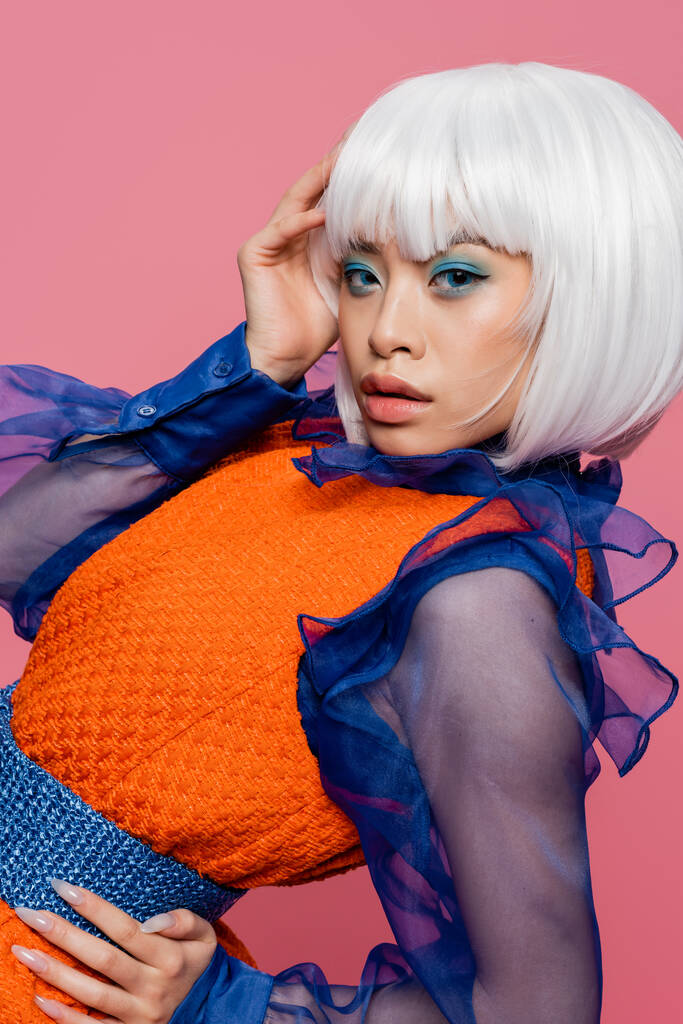 Pop art asijské modelu s make-upem a bílou parukou při pohledu na kameru izolované na růžové  - Fotografie, Obrázek