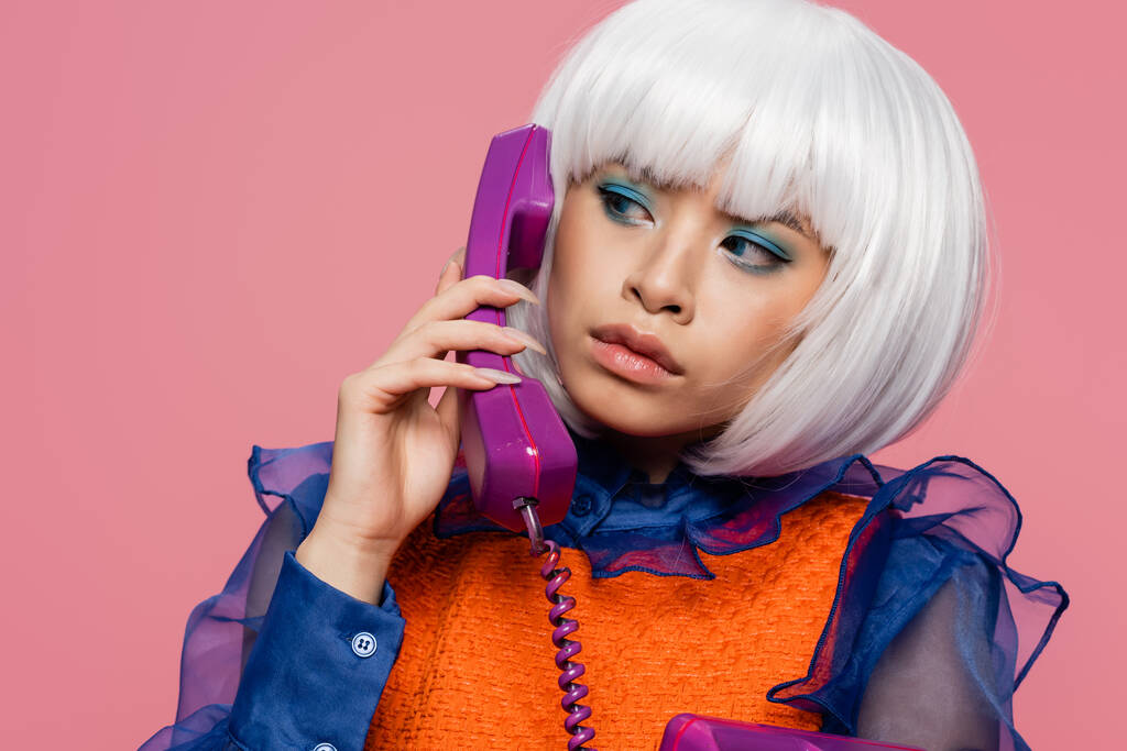 Ázsiai pop art nő fehér paróka beszél telefonon elszigetelt rózsaszín  - Fotó, kép