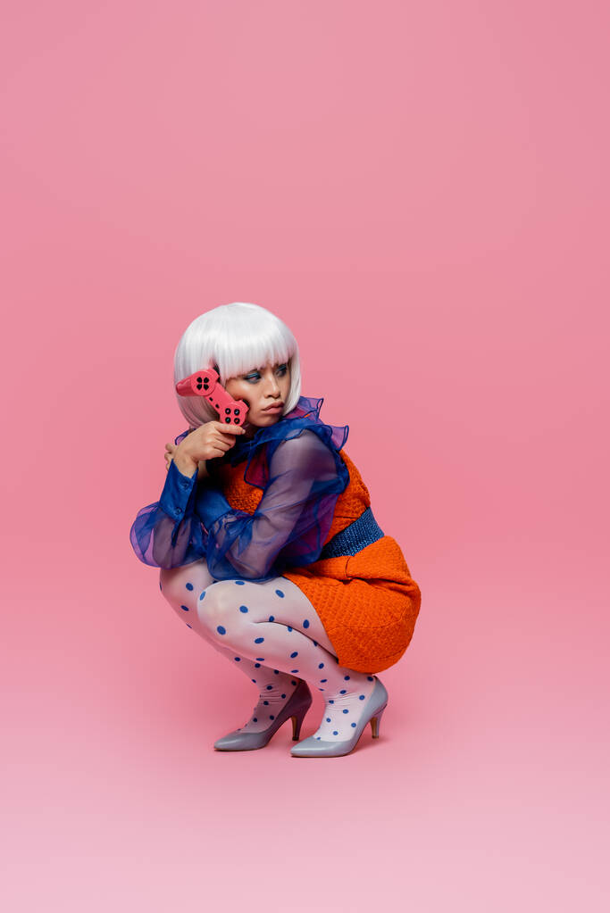 KYIV, UCRAINA - 10 DICEMBRE 2020: Donna pop art asiatica con joystick su sfondo rosa - Foto, immagini