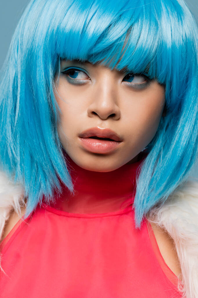 Retrato de mujer asiática en peluca brillante mirando hacia otro lado aislado en azul  - Foto, imagen