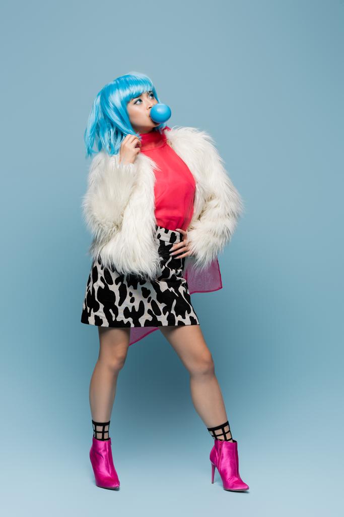 Модная азиатка в стиле поп-арта выдувает жвачку на голубом фоне  - Фото, изображение
