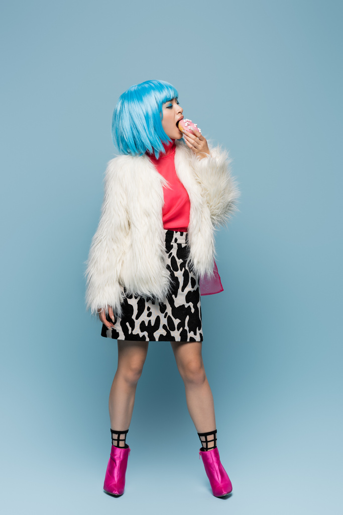 Plná délka stylové asijské pop art žena jíst koblihy na modrém pozadí  - Fotografie, Obrázek