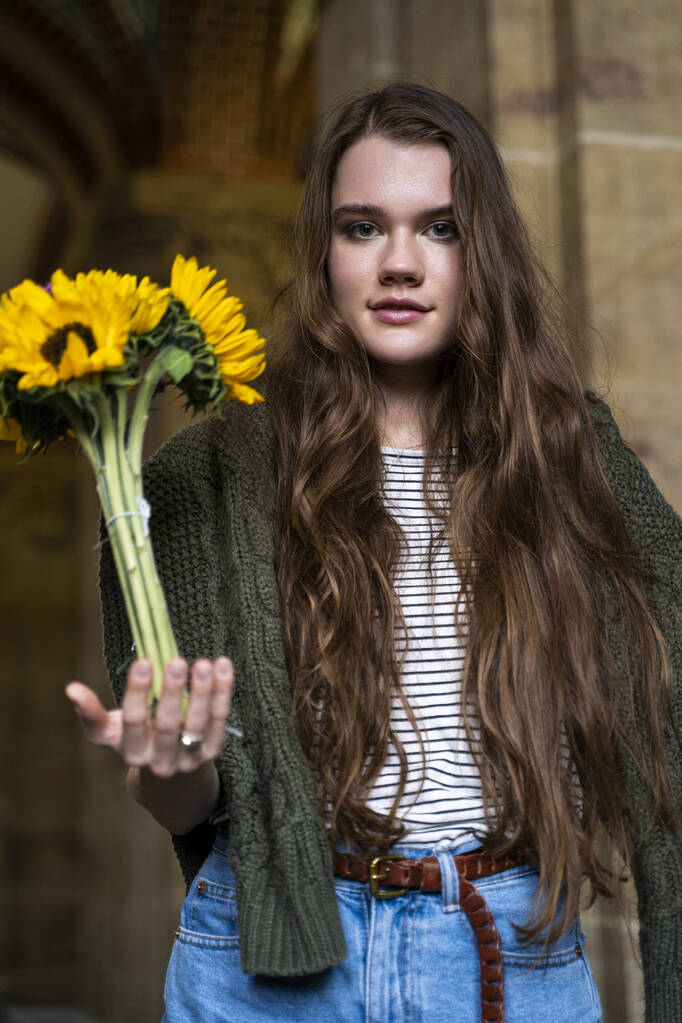 Junge brünette Frau mit einem Strauß frischer Sonnenblumen in der Hand - Foto, Bild