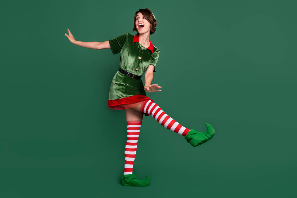 Comprimento total tamanho do corpo vista de menina alegre atraente vestindo elfo olhar dançando isolado sobre fundo de cor verde - Foto, Imagem
