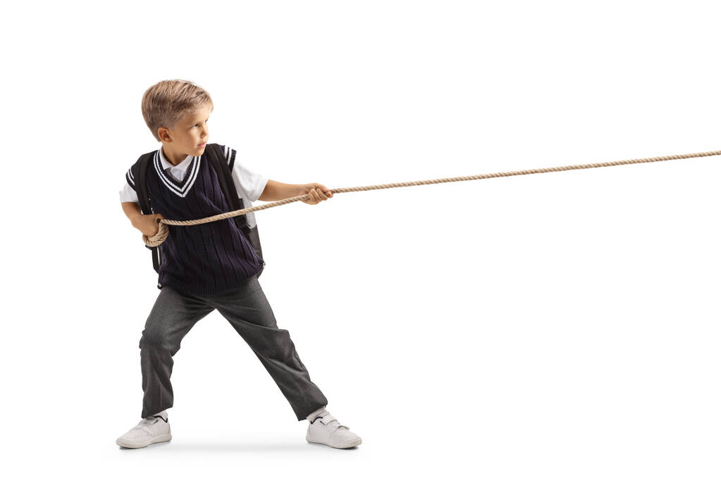 Full length profile shot of an angry schoolboy pulling a rope isolated on white background - Photo, Image