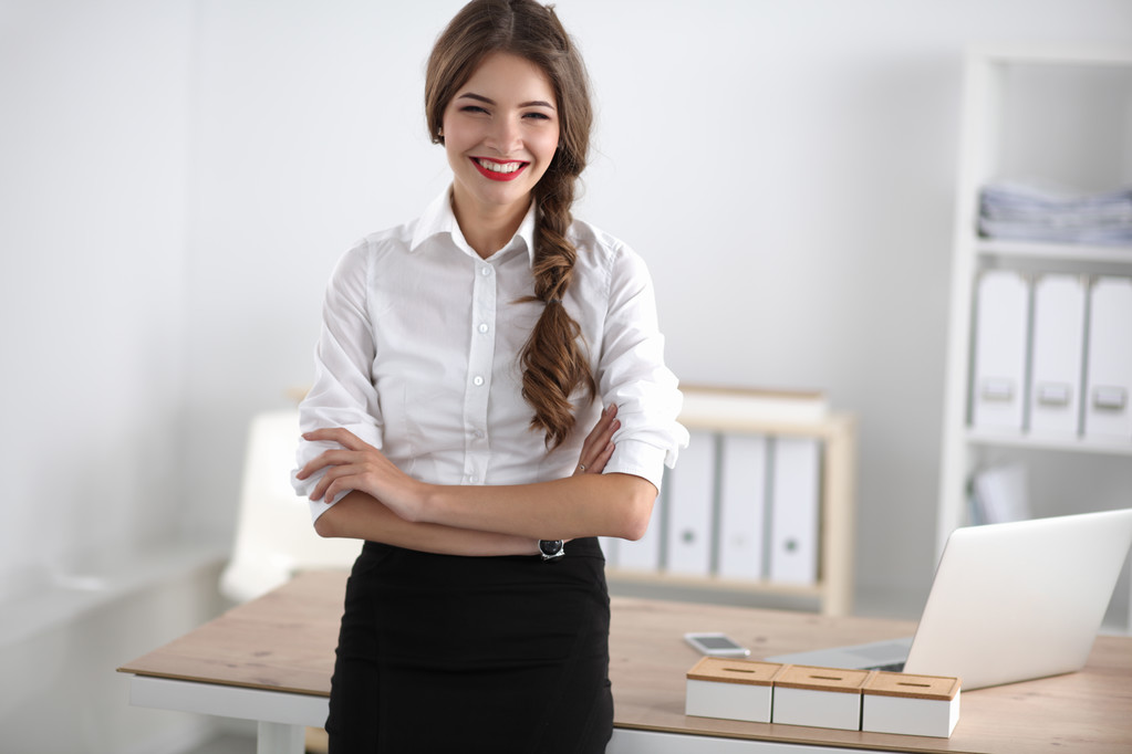 Atrakcyjna bizneswoman z skrzyżowanymi ramionami stojąca na stanowisku - Zdjęcie, obraz