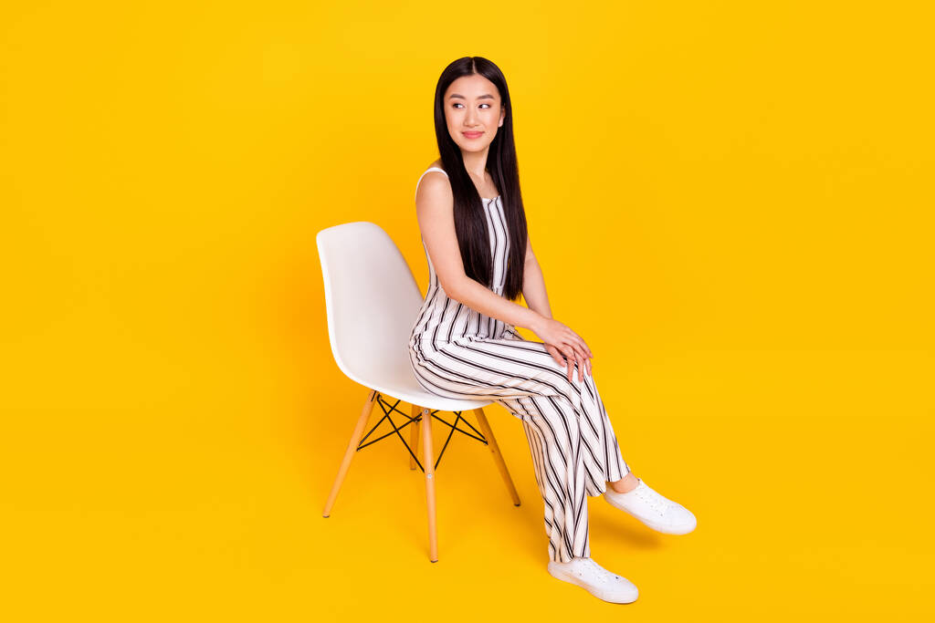 Teljes hossz testméret fotó fiatal lány ül a széken visel alkalmi általános megjelenésű copyspace mosolygó elszigetelt élénk sárga szín háttér - Fotó, kép