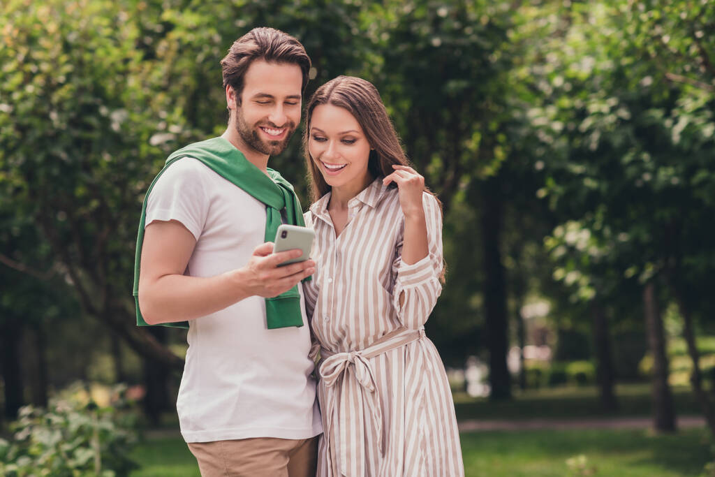 Foto portriat pareja joven sonriendo en verano con ropa casual navegar por Internet con teléfono móvil - Foto, imagen