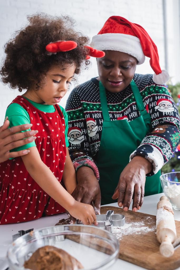 afrikkalainen amerikkalainen nainen jouluhattu pojantytär poro sarvet otsanauha ruoanlaitto keittiössä - Valokuva, kuva