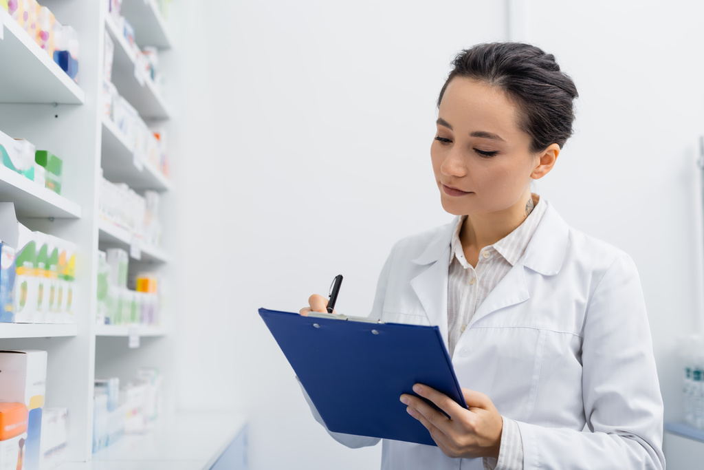vytetovaný lékárník v bílém plášti na podložce v lékárně - Fotografie, Obrázek