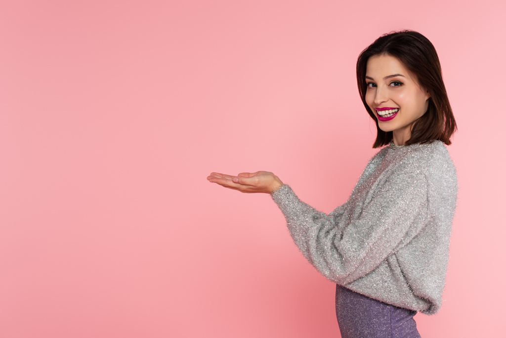 Glückliche Frau im warmen Pullover, die Hände auf rosa gestreift  - Foto, Bild