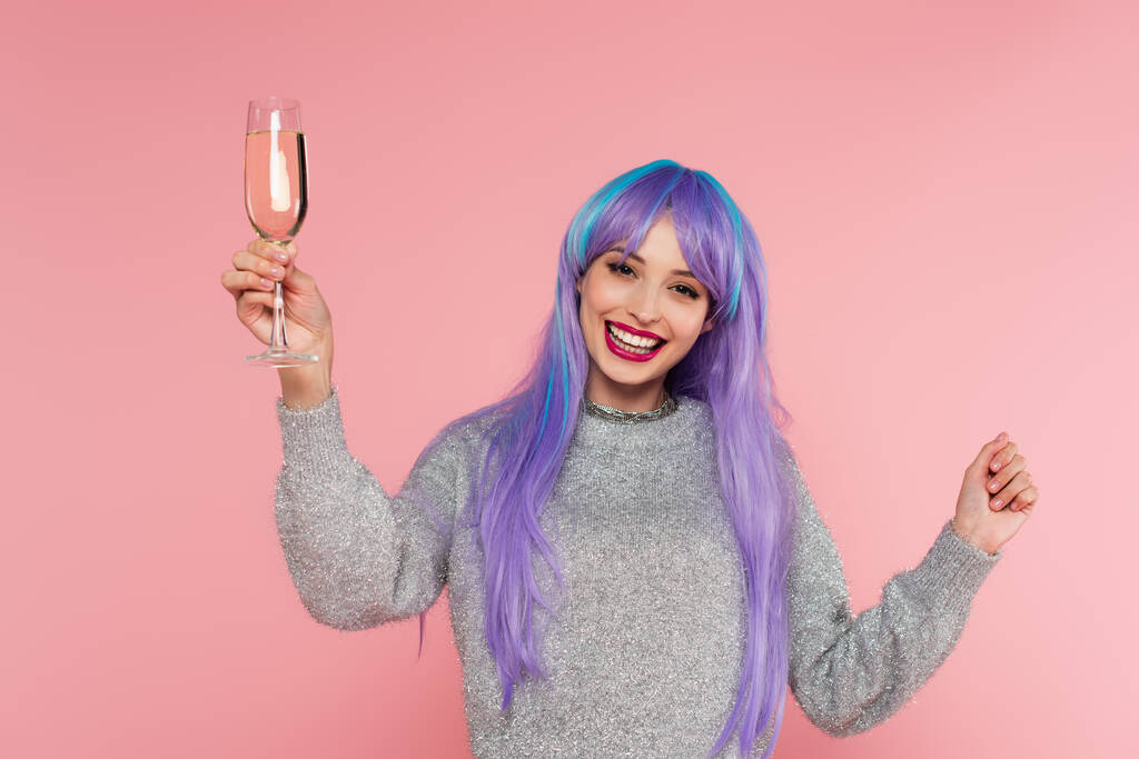 Позитивна стильна жінка з фарбованим волоссям, що тримає шампанське ізольовано на рожевому
  - Фото, зображення