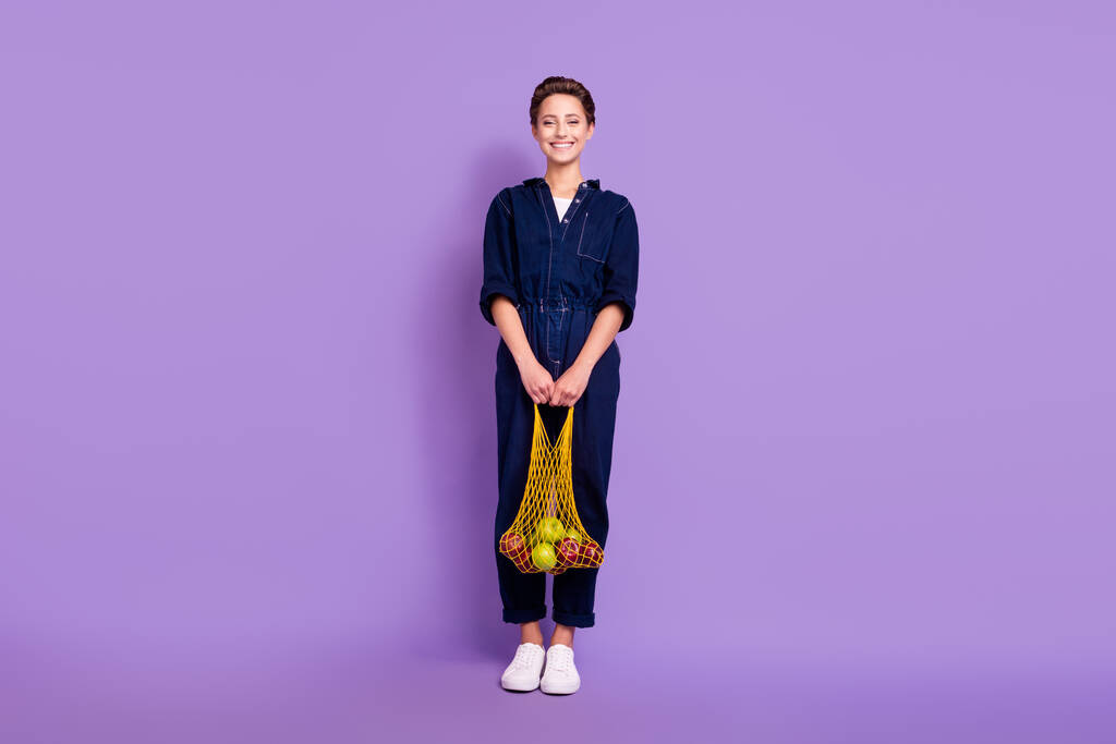 Täysikokoinen kuva nuorten hymyilevä hyvällä tuulella ympäristöystävällinen tyttö ostoksia net laukku eristetty violetti väri tausta - Valokuva, kuva
