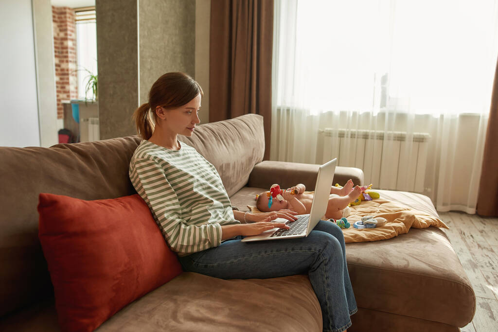 Beautiful woman doing online shopping staying at home with her child - Photo, Image