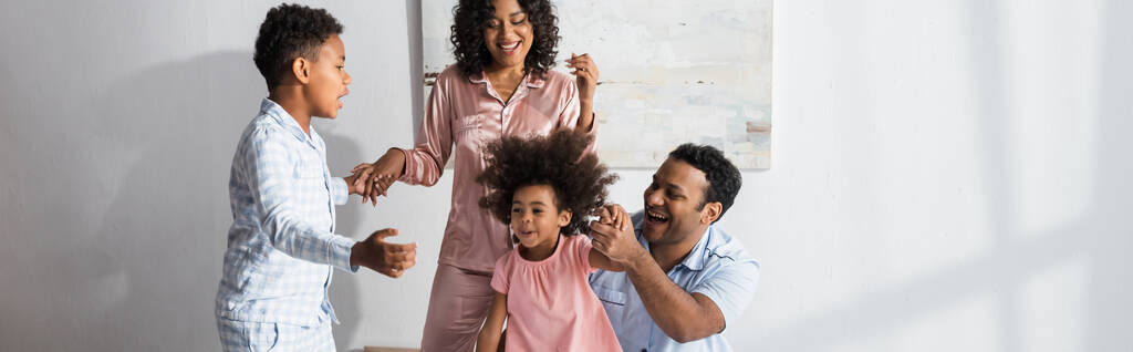 fröhliche afrikanisch-amerikanische Familie Händchenhalten beim Spaß im Schlafzimmer, Banner - Foto, Bild