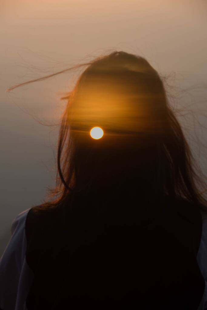 portrait of a beautiful young woman with long hair in a black dress on a background of a sunset - Foto, Bild