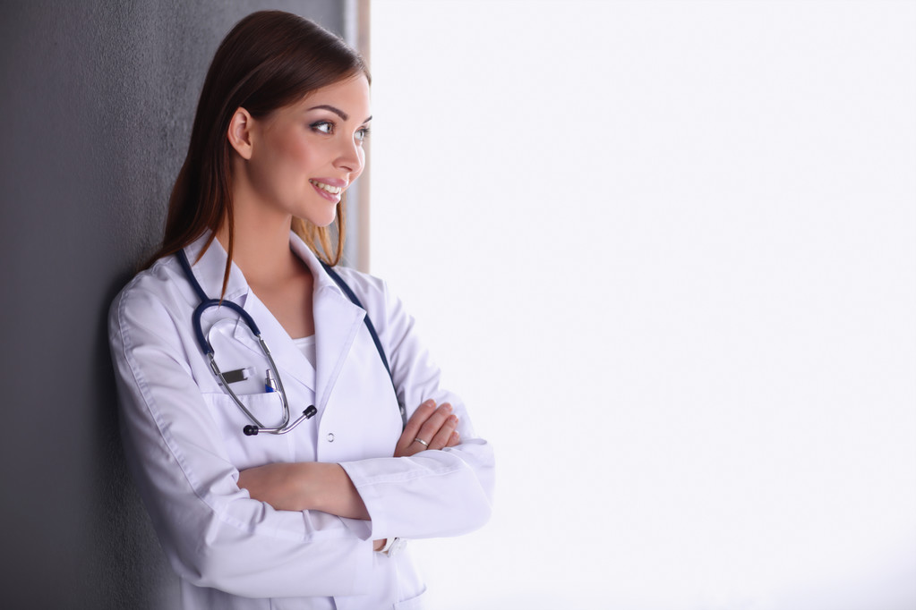 Médecin femme avec stéthoscope debout près du mur gris
 - Photo, image