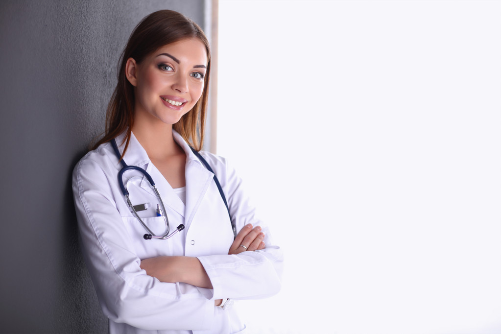 Médico mujer con estetoscopio de pie cerca de la pared gris
 - Foto, Imagen