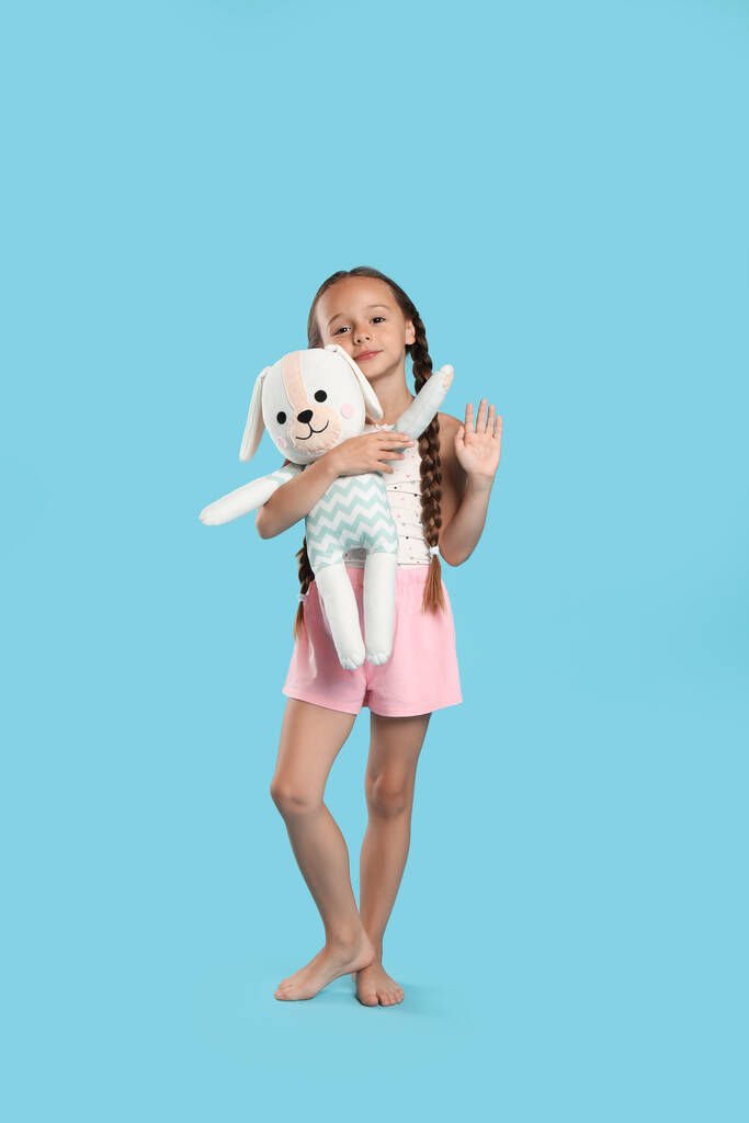 Cute girl noszenie piżamy z zabawką na jasnoniebieskim tle - Zdjęcie, obraz