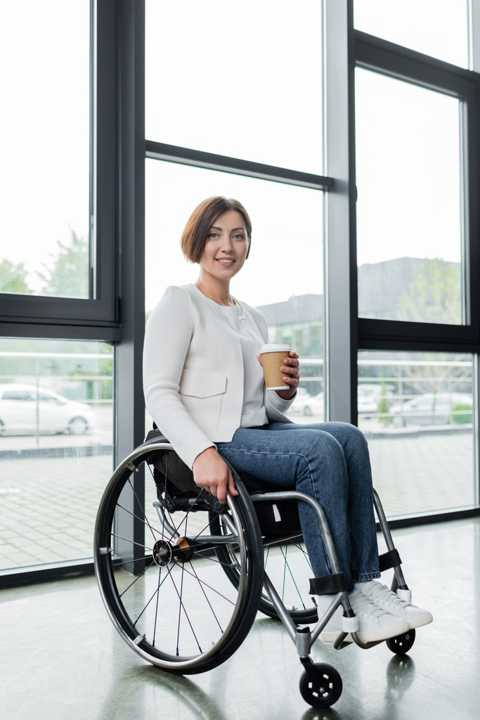 Ganzkörperansicht der Geschäftsfrau im Rollstuhl mit Imbissgetränk im Büro - Foto, Bild